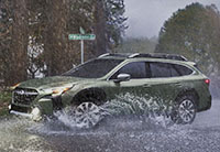 A 2023 Subaru Outback driving through heavy rain.