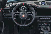 Červený středový pruh volantu a červeno-šedé prošívání na přístrojové desce Porsche 911 Carrera GTS Cabriolet America Edition 2023.